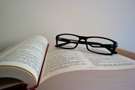 Imagte d'un llibre obert amb unes ulleres damunt